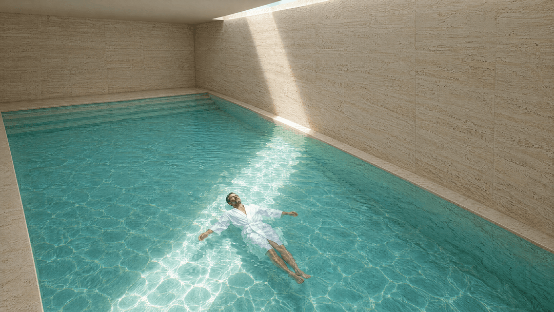 A guest floating in a travertine hotel pool under a single band of sunlight